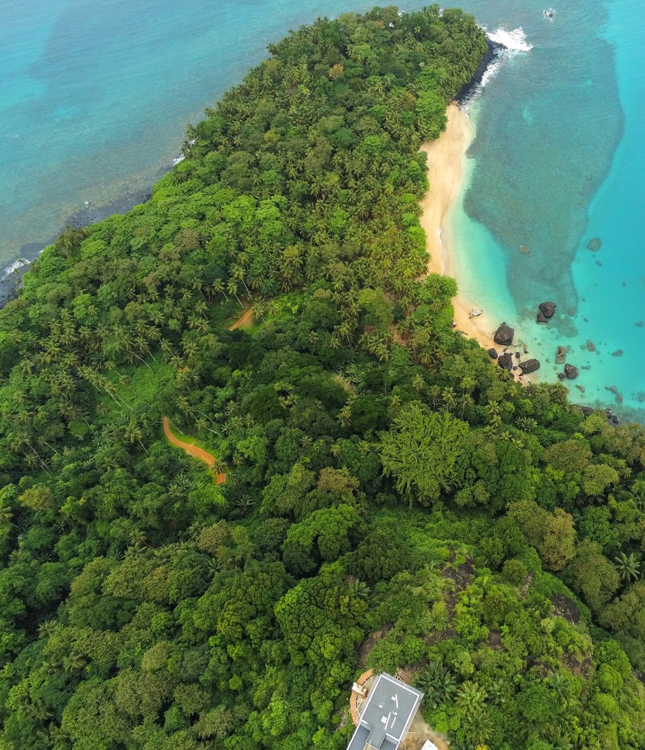 Vista aérea de la isla de São Tomé y Príncipe, con abundante vegetación, una playa de arena blanca y aguas cristalinas