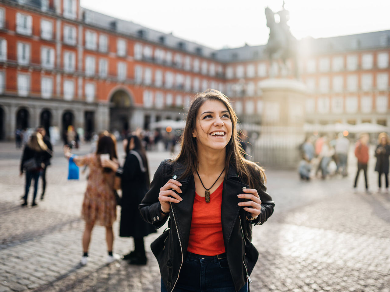 Chica feliz con una mochila deambulando por la Plaza Mayor, en el centro histórico de Madrid