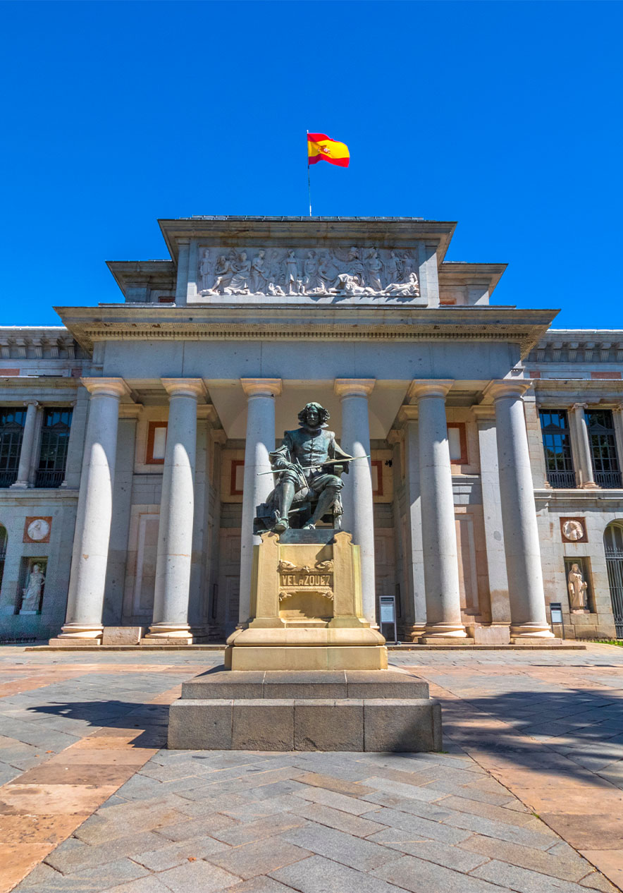 Fachada del Museo del Prado, con una estatua en la entrada y la bandera de España en la parte superior