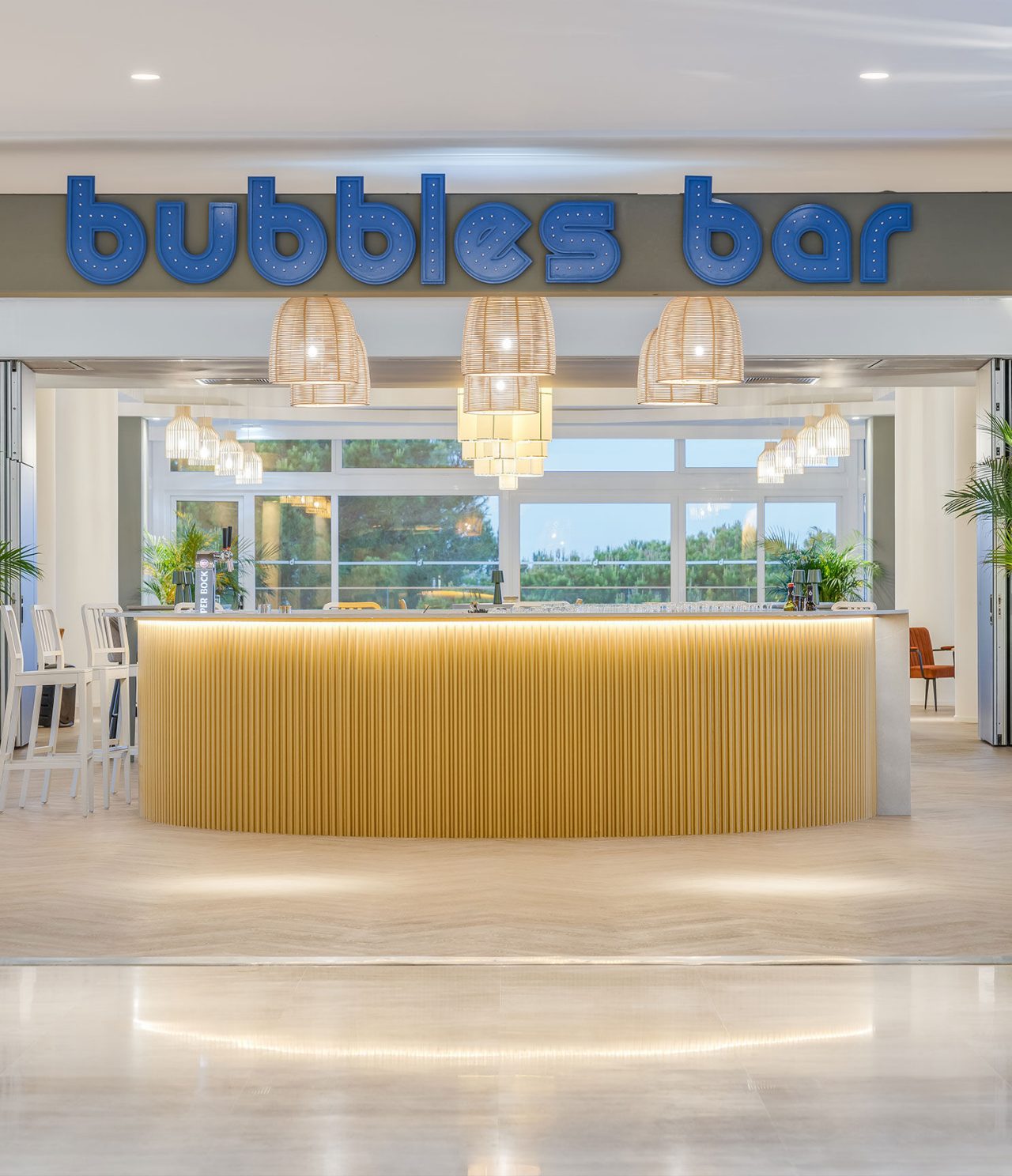 El bar Bubbles, del Hotel Todo Incluido en el Algarve, tiene un mostrador redondo de madera clara con el logotipo