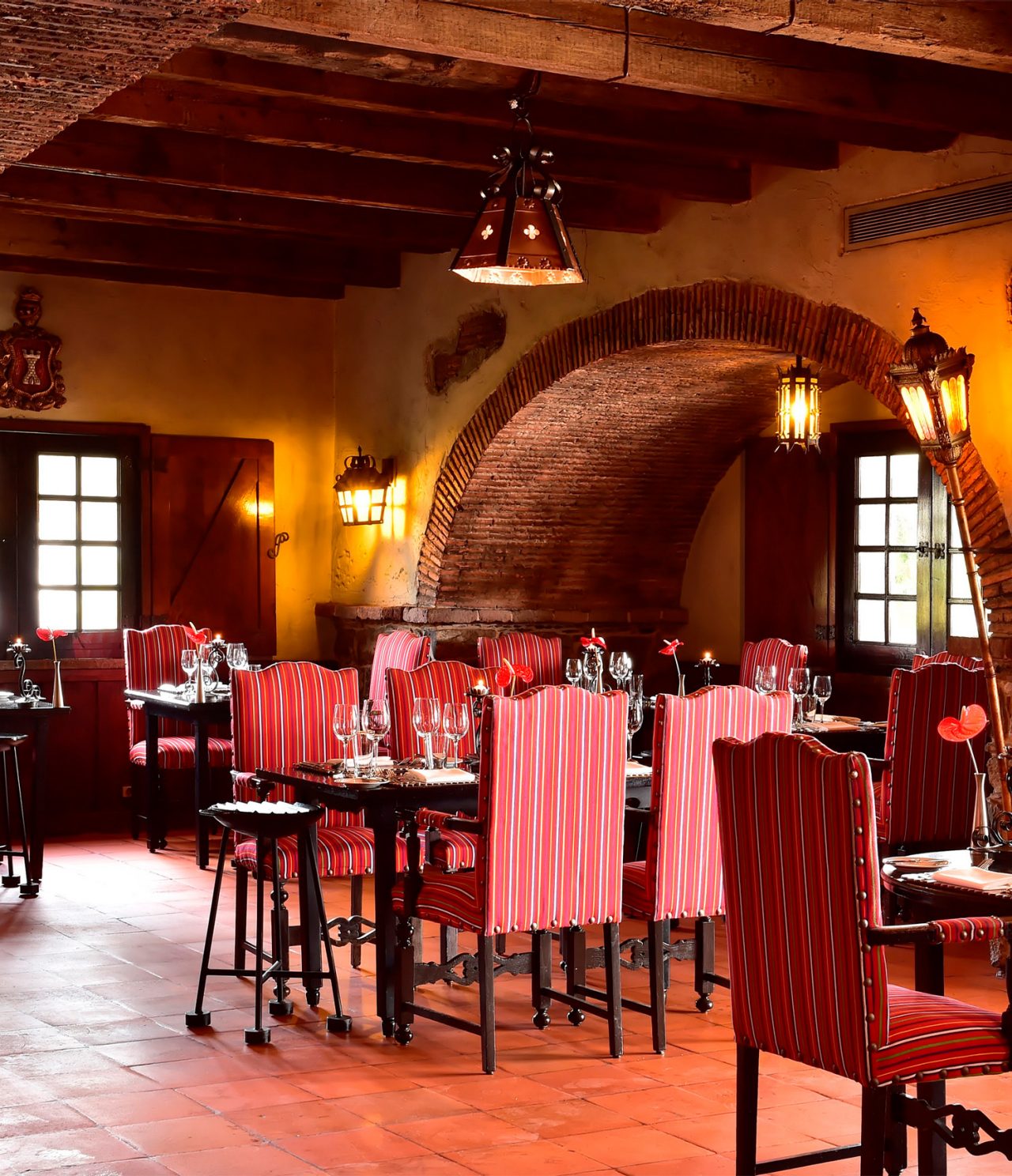 El restaurante Taverna Grill, del Hotel 5 Estrellas en Madeira, cuenta con un amplio espacio con sillas rojas y lámparas