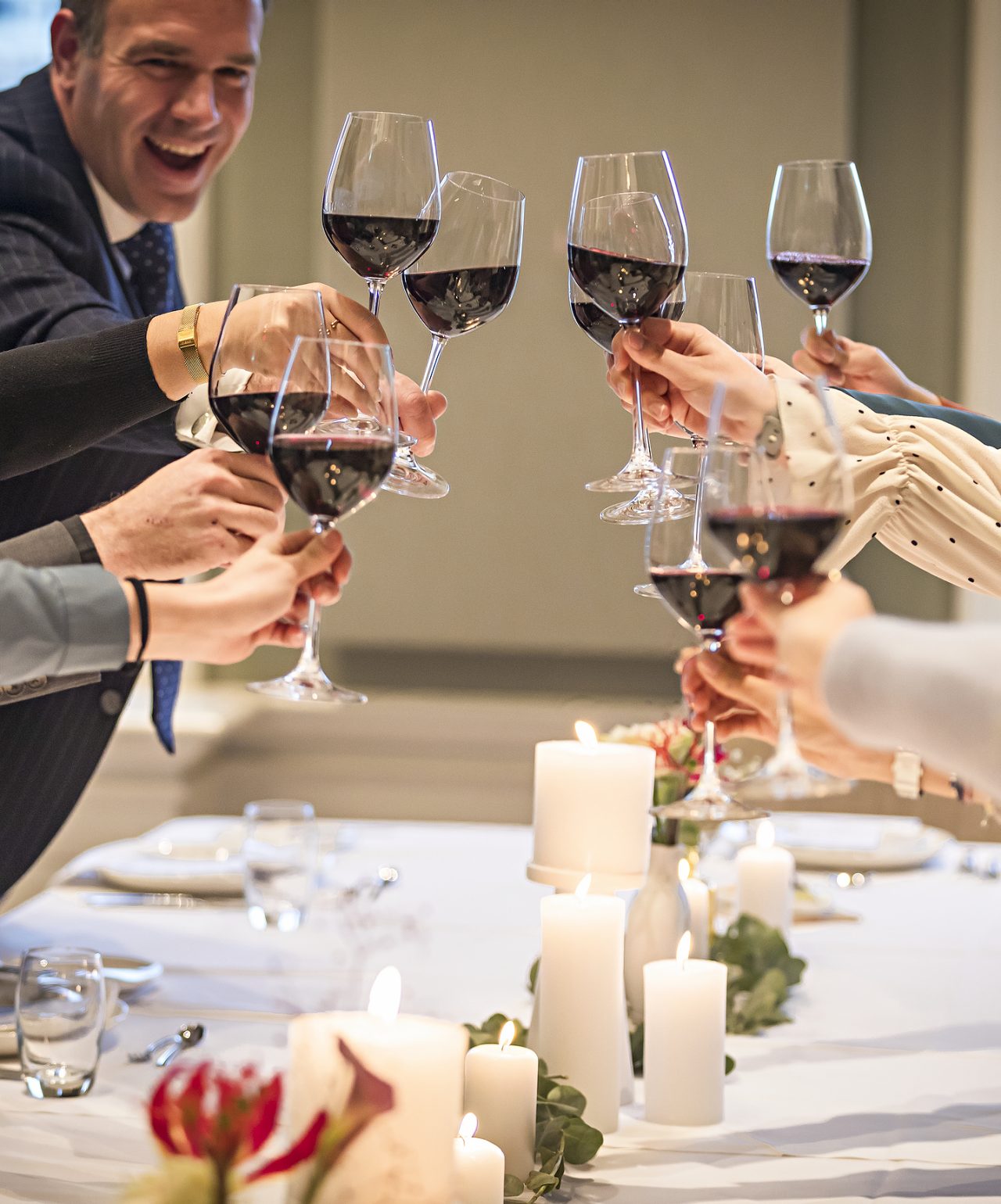 Los invitados brindan con copas de vino tinto en una boda con decoración elegante en el Pestana Hotel Group