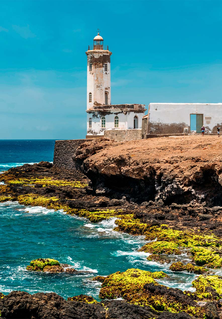 Farol costeiro em Cabo Verde, sobre penhascos rochosos com o mar azul ao fundo
