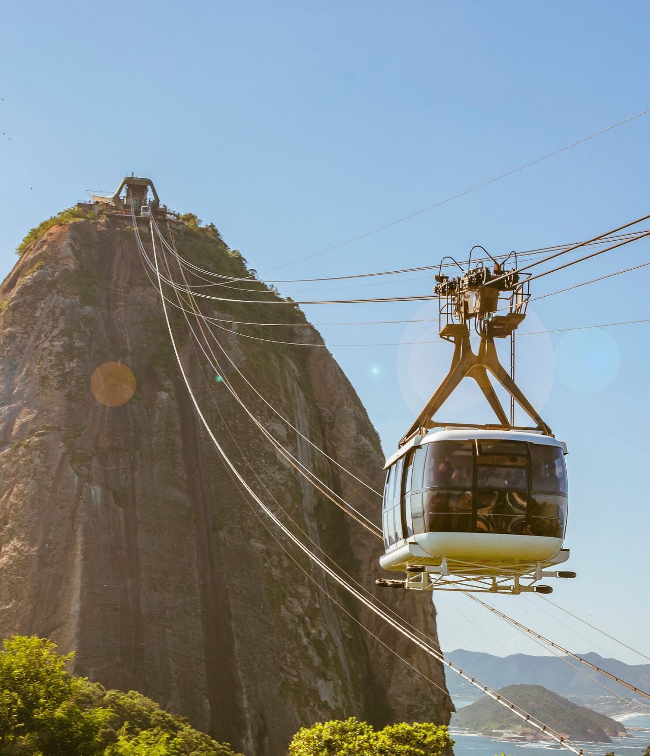 Vista do teleférico no Rio de Janeiro, que vai em direção de uma colina alta, com o mar no fundo