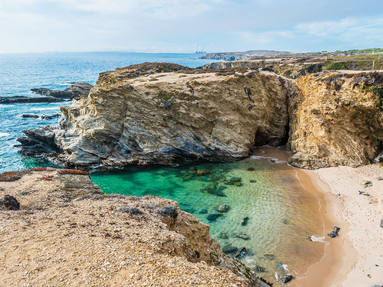 Praia escondida entre falésias no Alentejo, com águas cristalinas e areia branca, ideal para relaxar