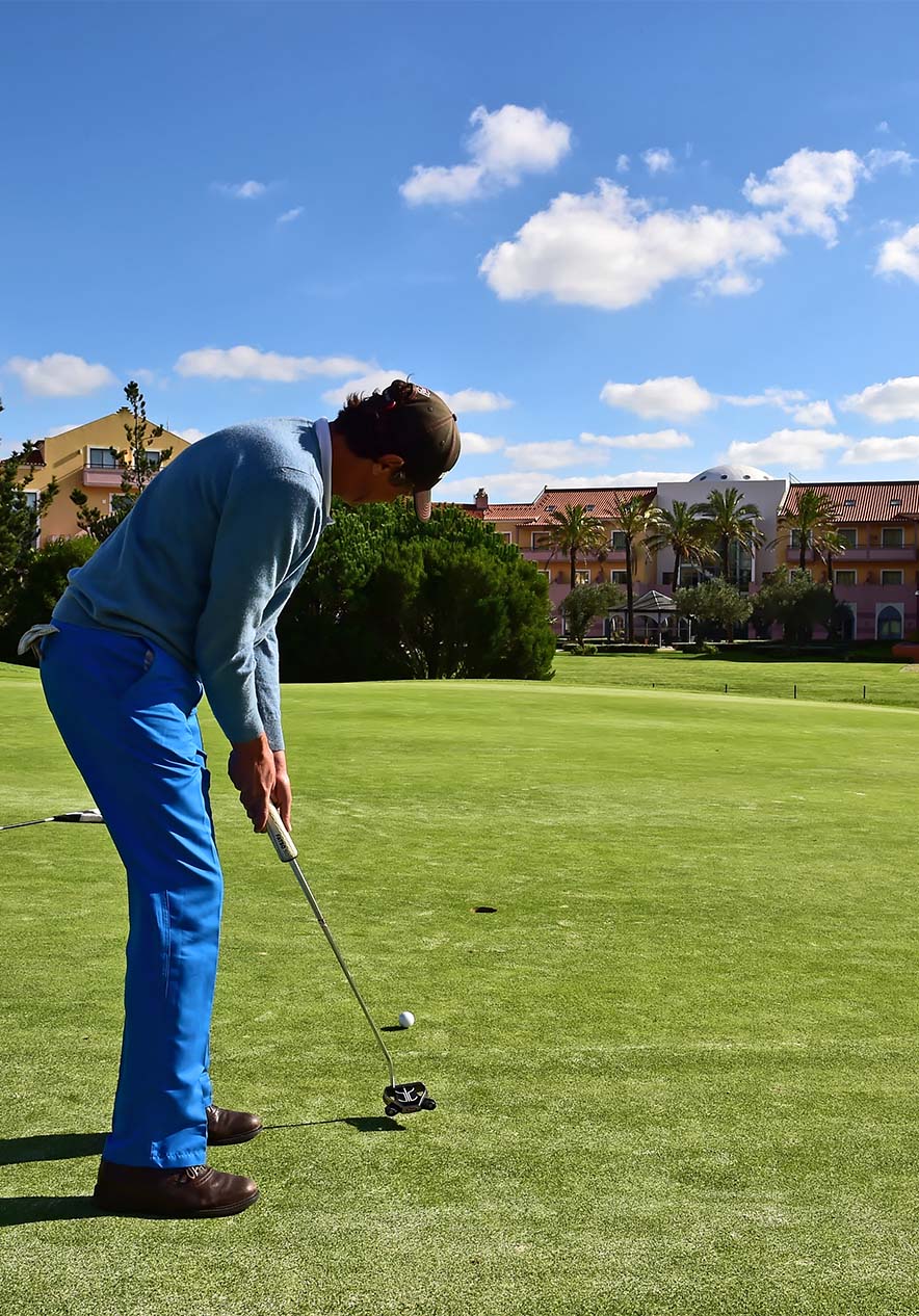 Num campo verde de golfe, um homem prestes a dar uma tacada, concentrado e com postura perfeita