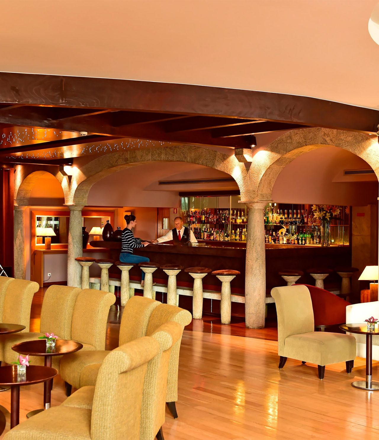 O bar Taverna, do Hotel 5 Estrelas na Madeira, tem um balcão com bancos e funcionário a servir um cocktail a uma pessoa