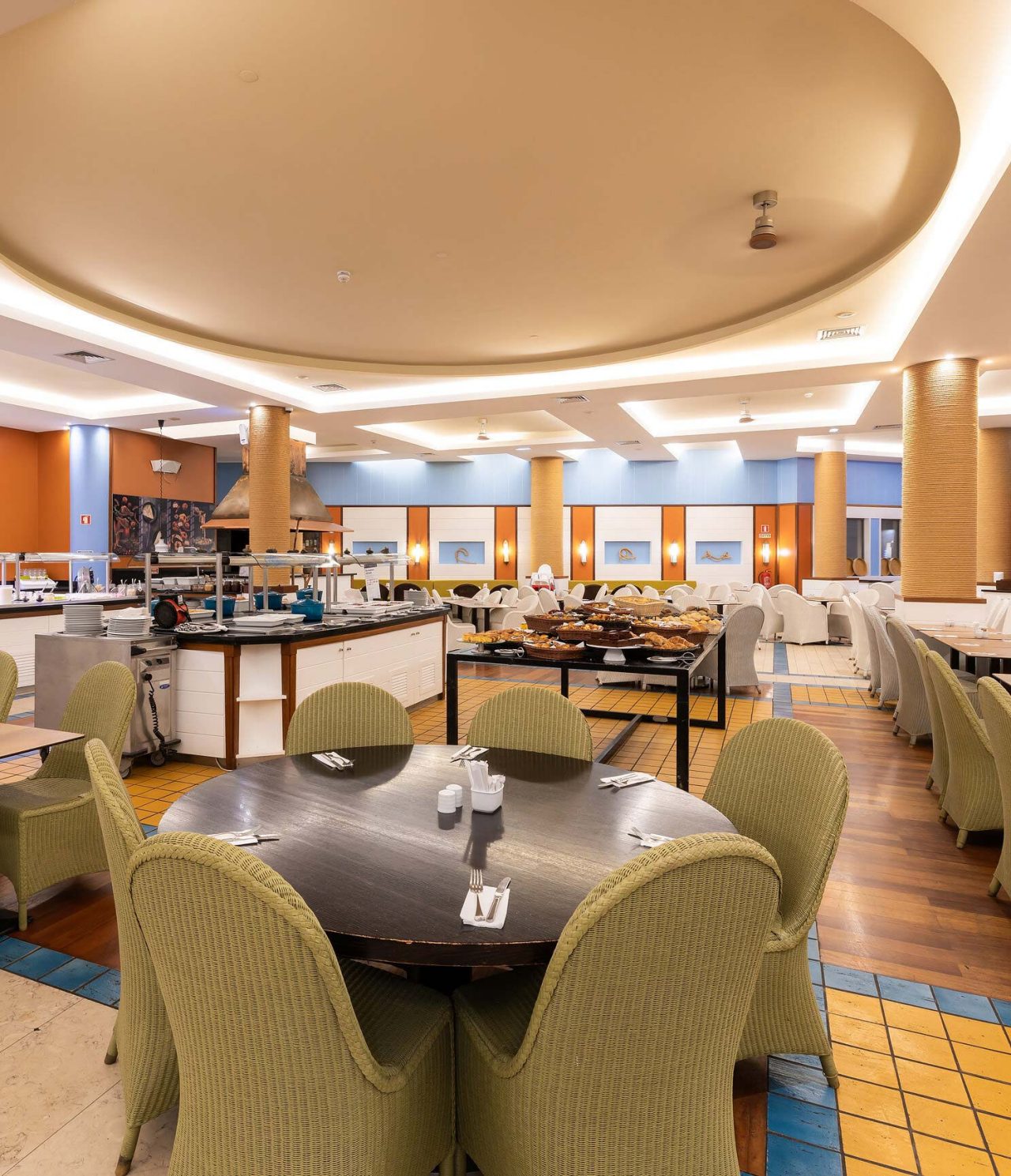 O restaurante Marés, do Resort de 5 Estrelas no Porto Santo tem um espaço amplo com paredes amarelas e cadeiras verdes