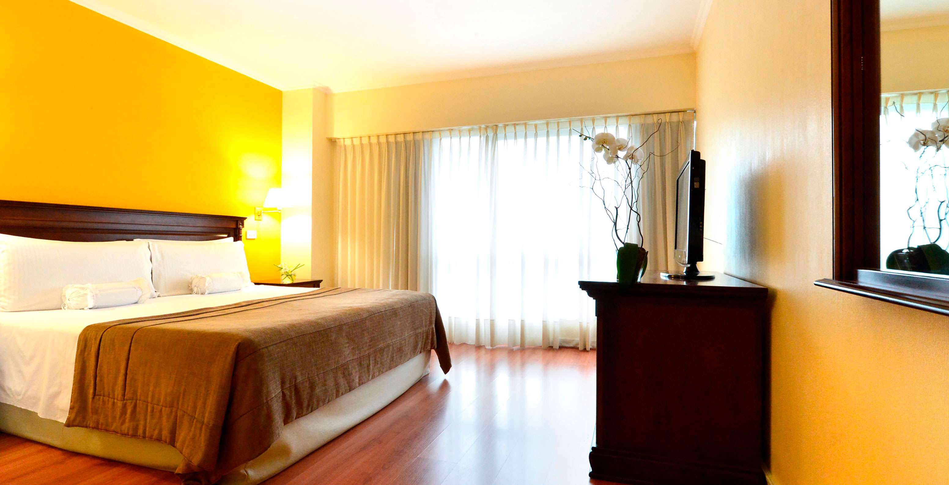 The Queen Standard at Pestana Buenos Aires has a double bed, a TV, a mirror, and a bedside table with a lamp