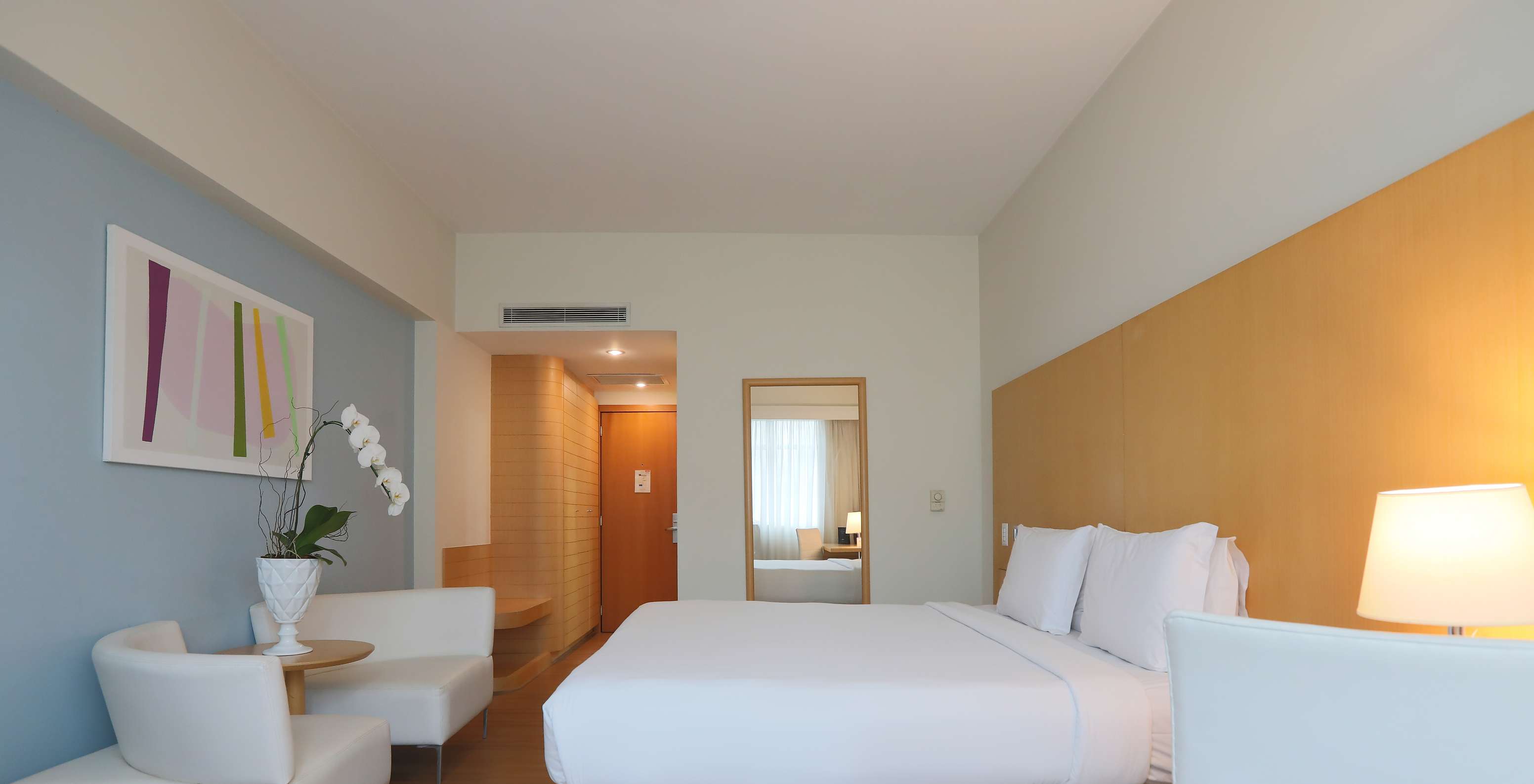 The Queen Standard at Pestana Curitiba has a double bed and two single sofas at the foot of the bed
