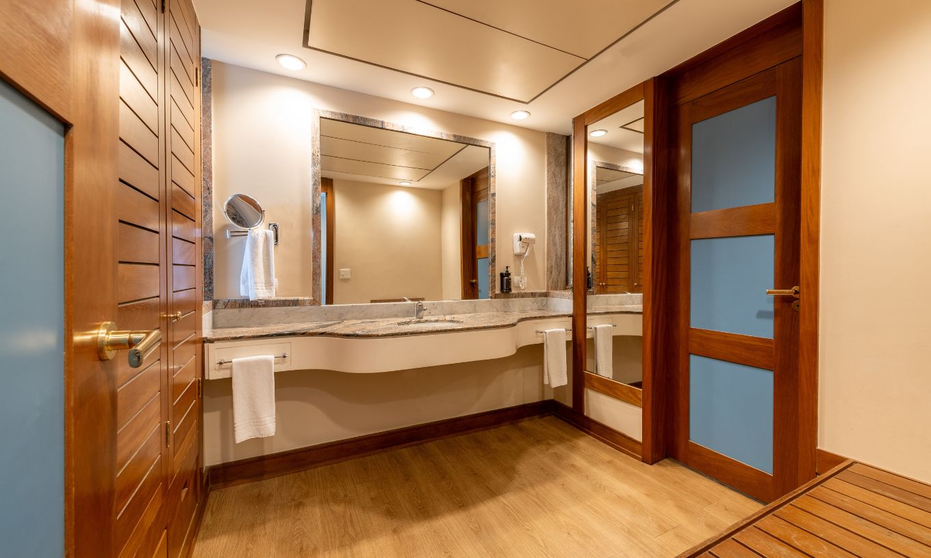 The Deluxe at Pestana São Paulo has a bathroom with a large sink with a mirror, a hairdryer, and towels