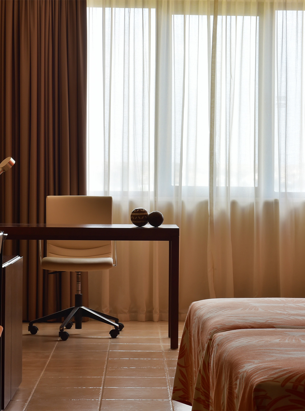 The Standard room at Pestana Tropico features a desk with lamp and a chair, and an armchair