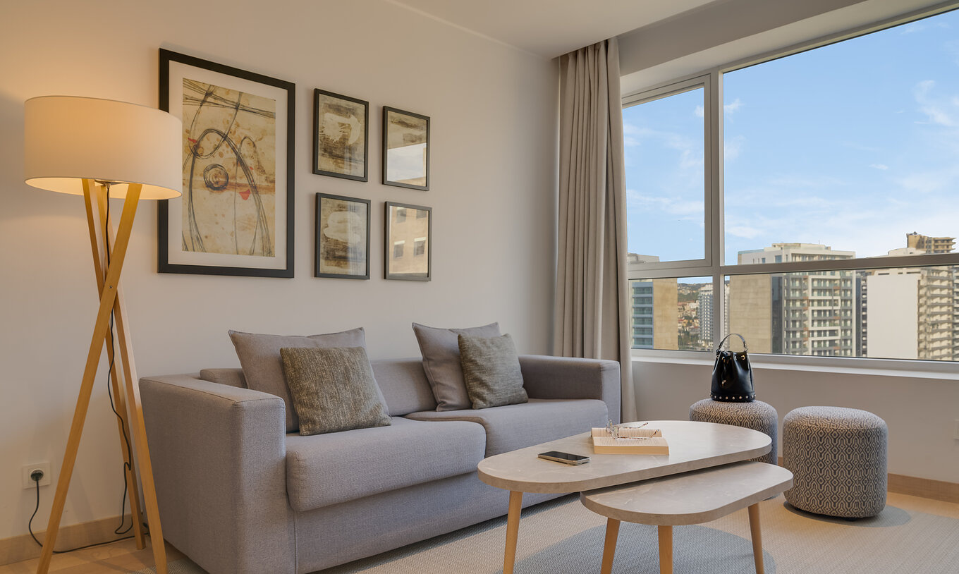 The Suite of Pestana Tanger City Center features a gray sofa, two side tables, a tall floor lamp, and pictures