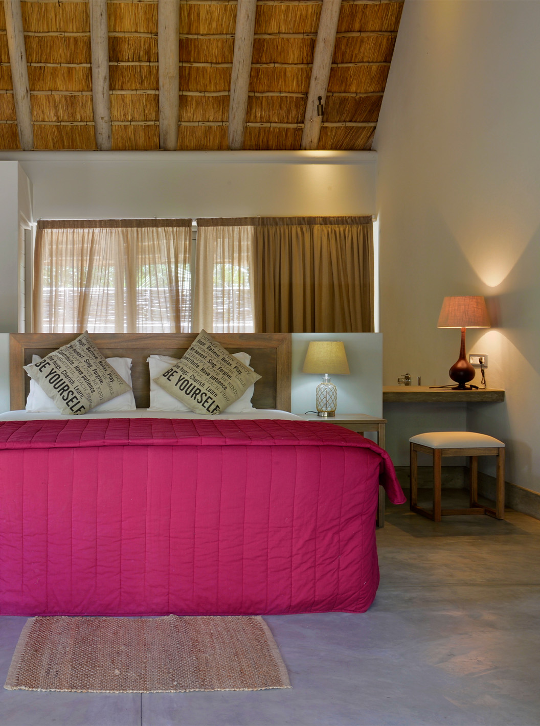 T2 Villas at Pestana Bazaruto Lodge are quite spacious with a double bed with red bedspread and windows around