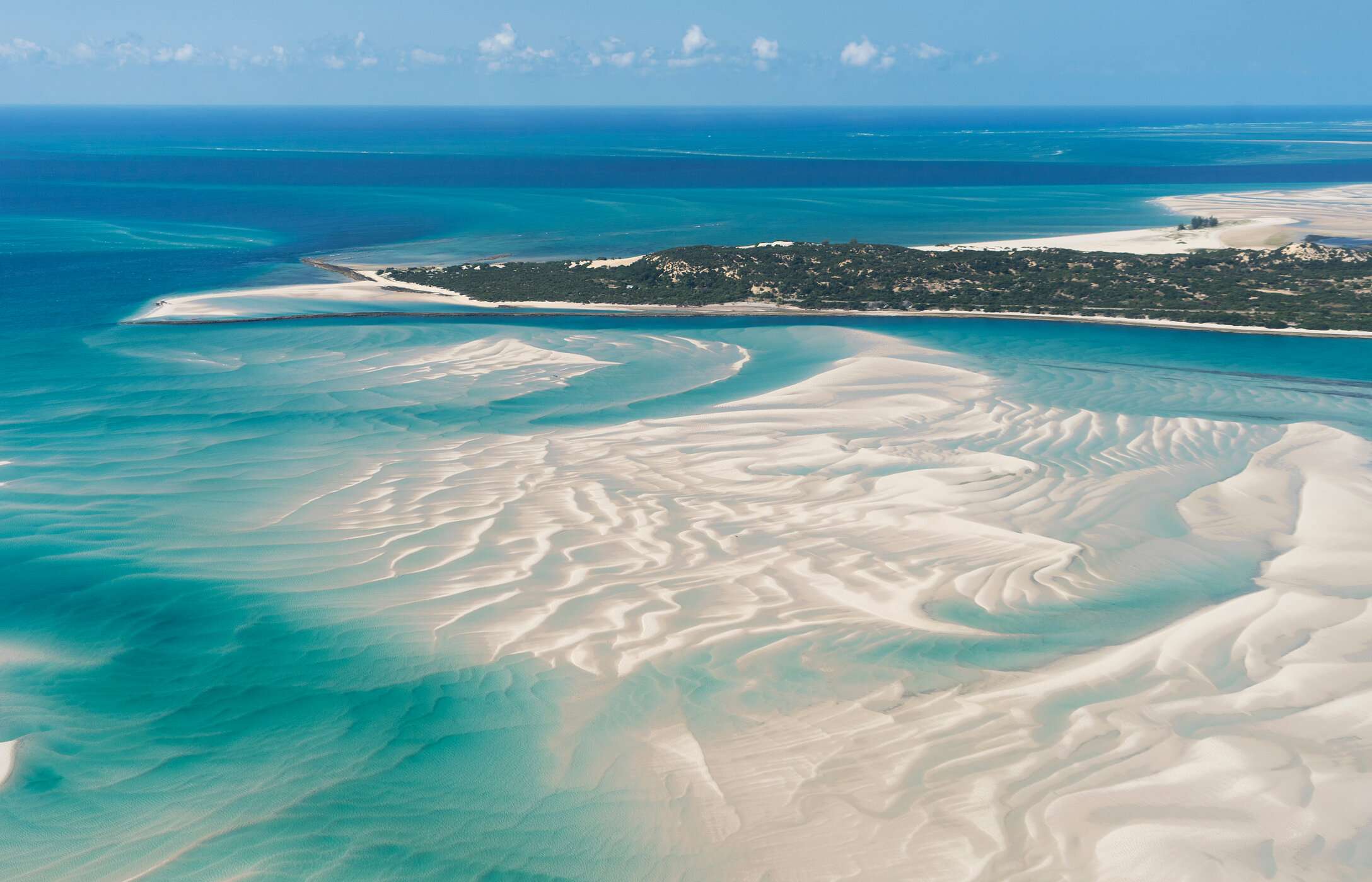 Aerial view of Vilankulo Island, Mozambique, with clear waters, sandbanks in the sea, and vegetation in the background.