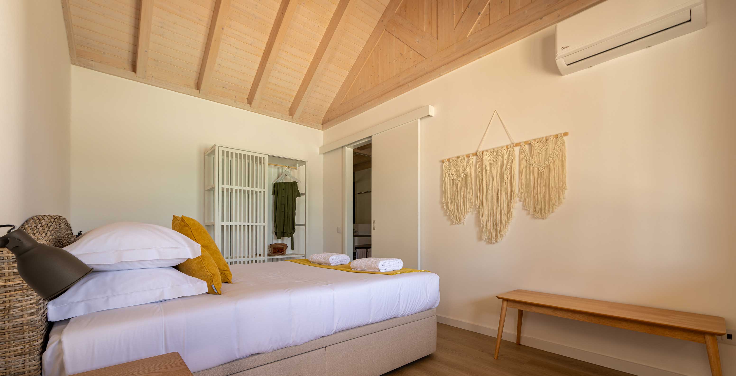 The Standard Green Villa at Pestana Comporta Village Residences has a minimalist bedroom with a bed and a bench
