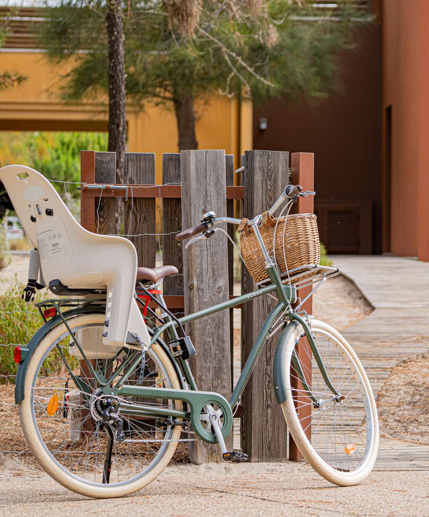 A bicycle with a child seat in the back and a wicker basket in front leaning against a tree at Pestana Tróia Eco Resort