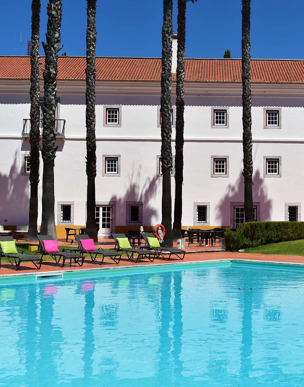 Outdoor pool of Pousada Convento Beja, a historic hotel in Alentejo, with several sun loungers with cushions