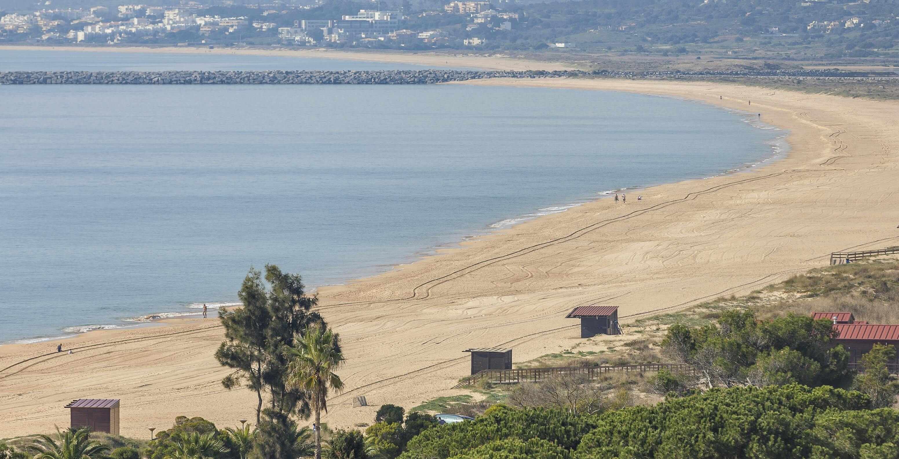 Alvor Beach in Algarve has golden sand, crystal-clear water, a boardwalk, and dunes