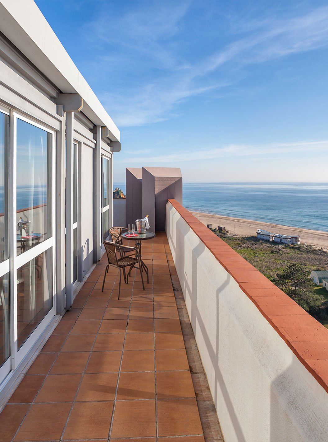 The T1 Sea View Apartment at Pestana Alvor Atlântico has a balcony with a table and two chairs, overlooking the beach and sea
