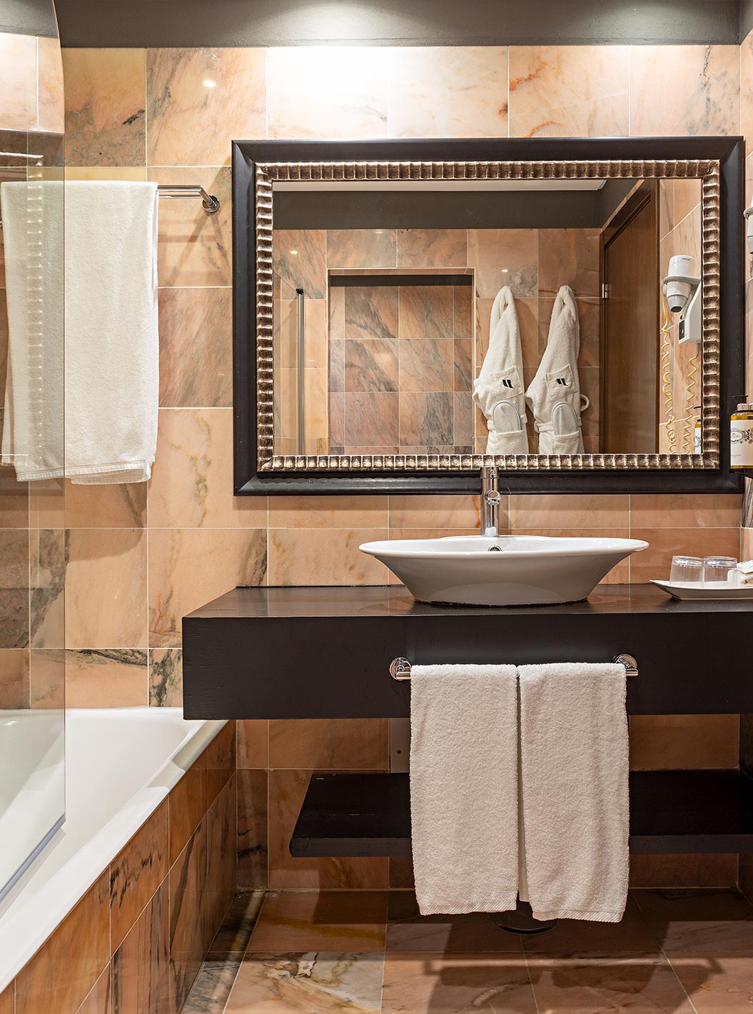 The Cliff Suite T1 at Pestana Alvor Praia has a bathroom with a bathtub, two bathrobes, and a hairdryer