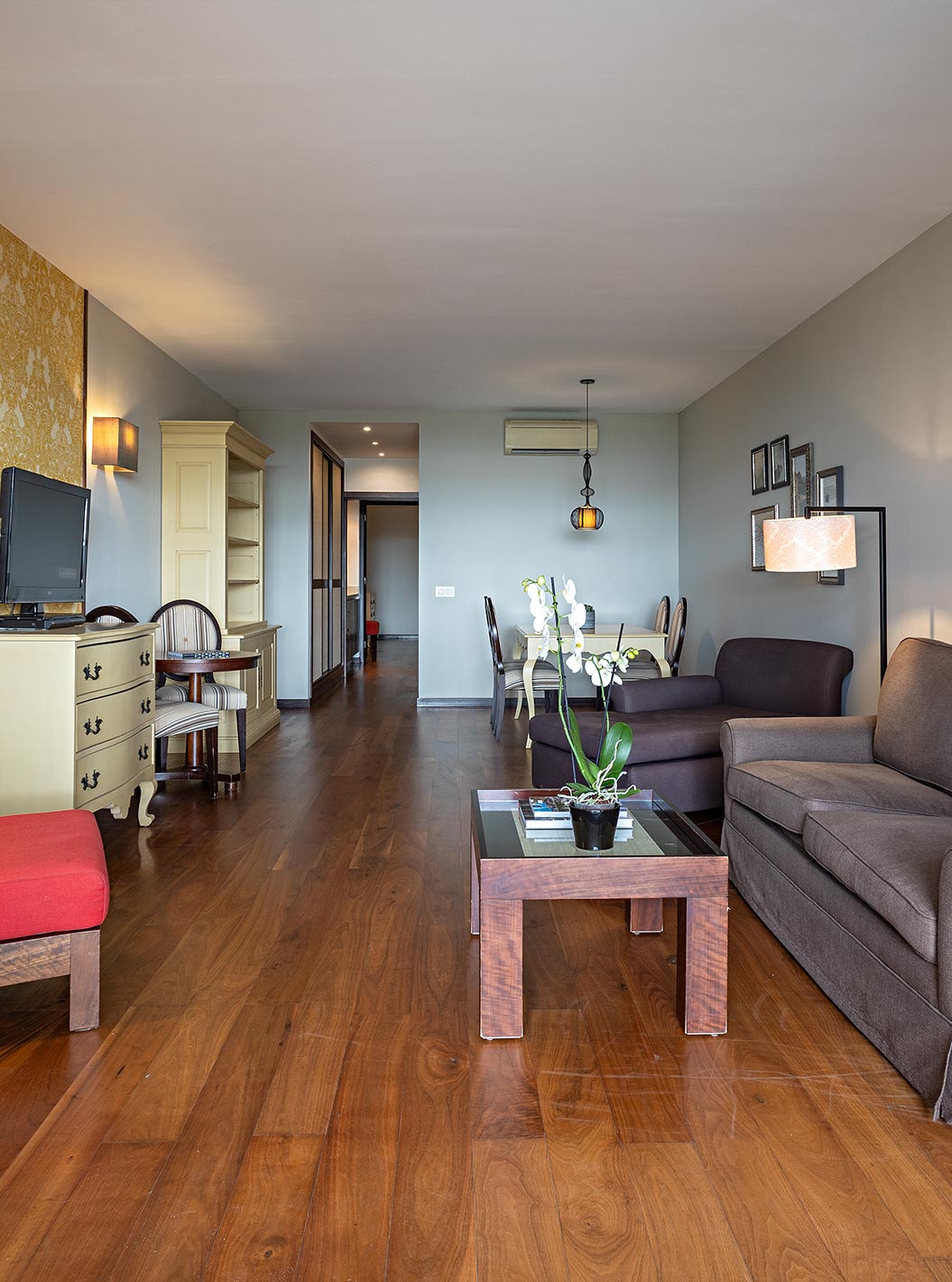 The Cliff Suite T2 at Pestana Alvor Praia has a living room with two sofas, wallpaper, a television, and a table