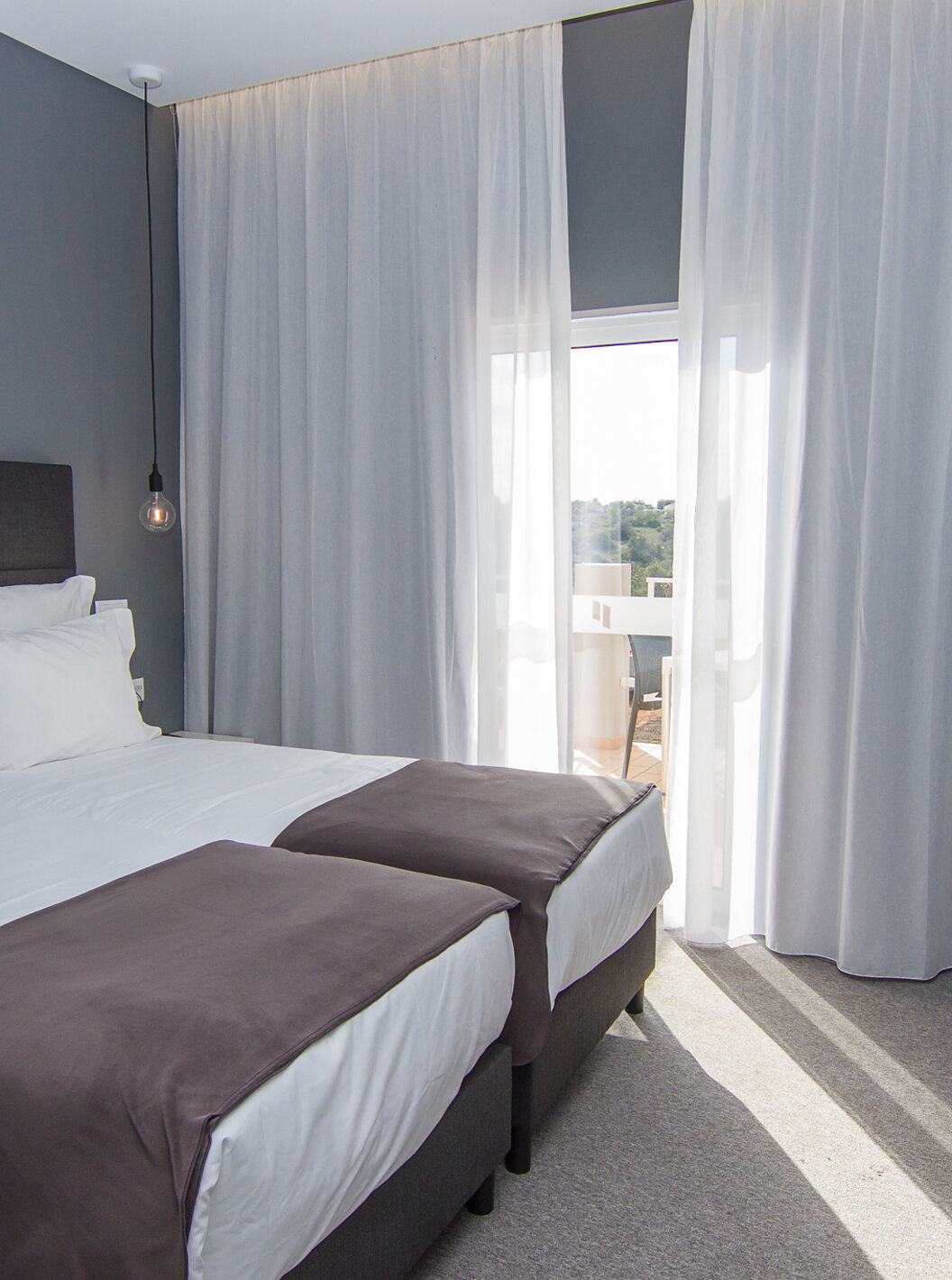 The Classic Pool View room at Pestana Gramacho Residences features two single beds, a chair, and a window