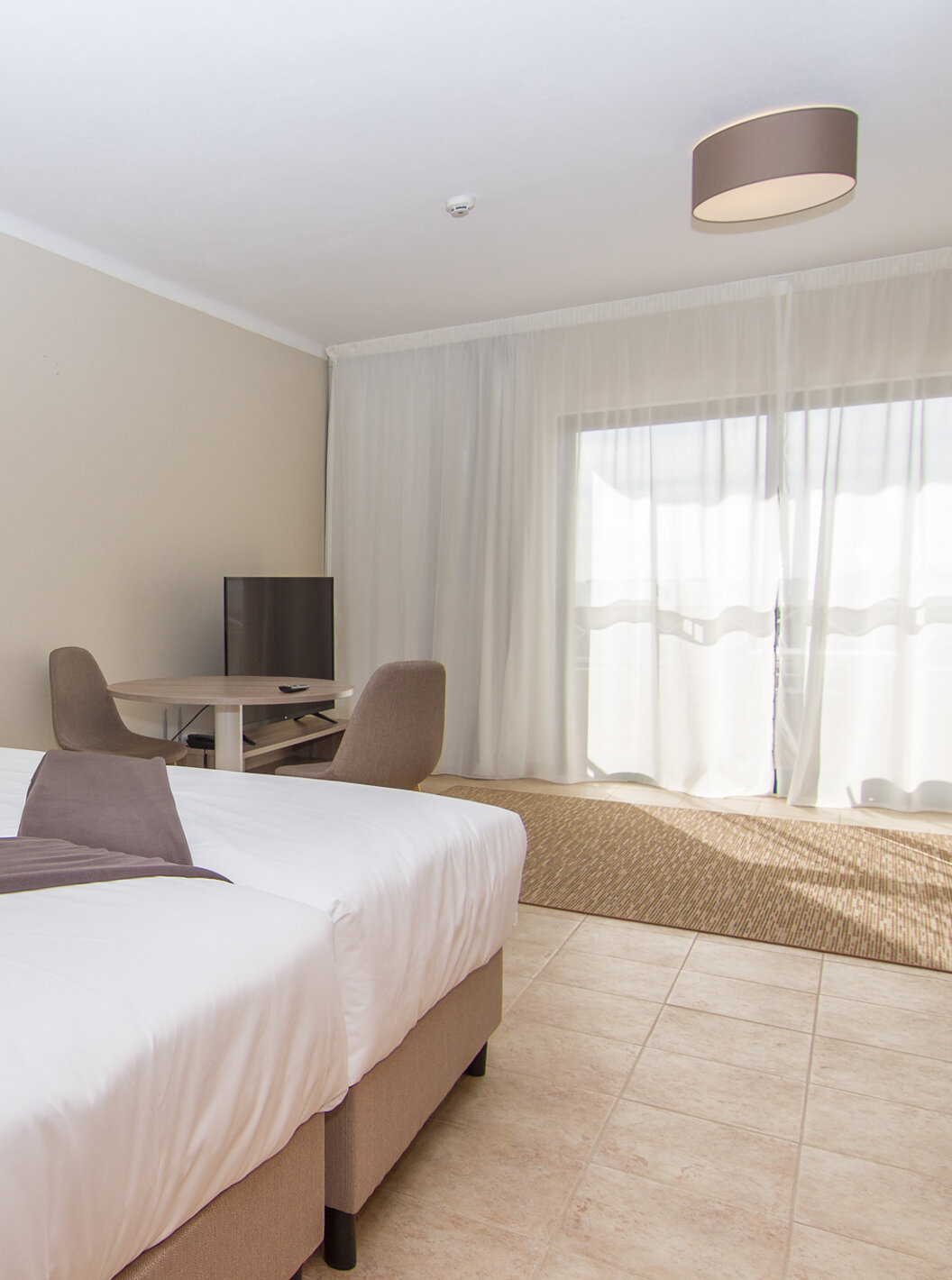 The Studio at Pestana Gramacho Residences features two single beds, a table with two chairs, and a window