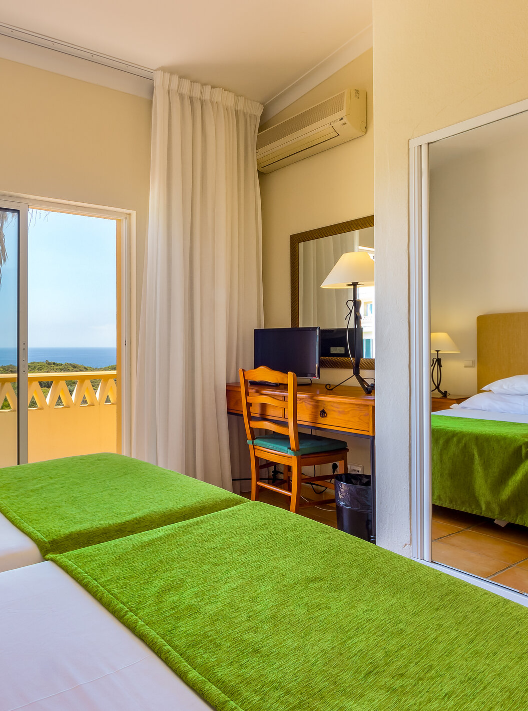 The T2 Apartment Premium do Pestana Palm Gardens has two beds with a green bedspread and a balcony with sea view