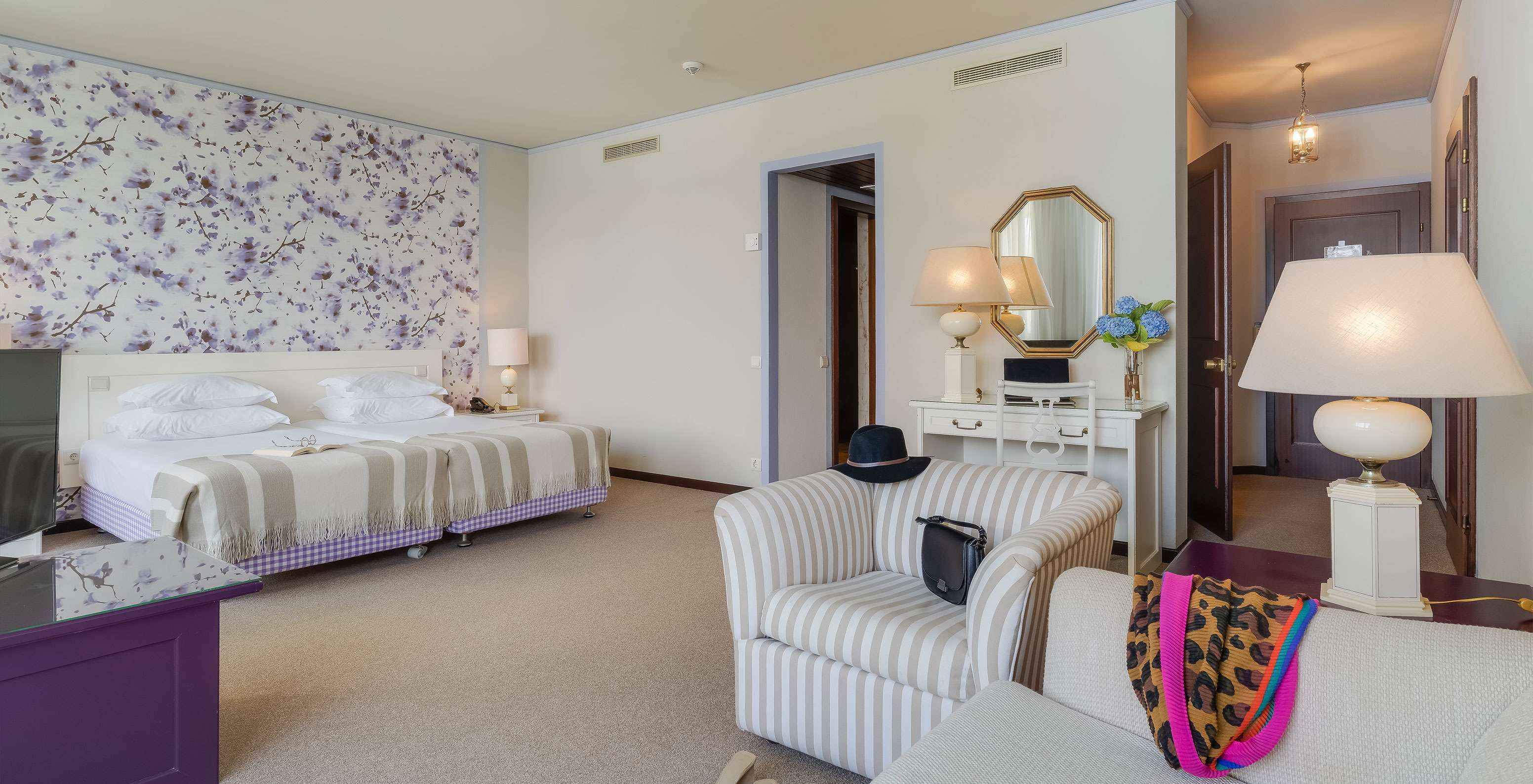 In the Junior Sea View Suite at Pestana Bahia Praia, beds are next to the balcony, with views of gardens and sea