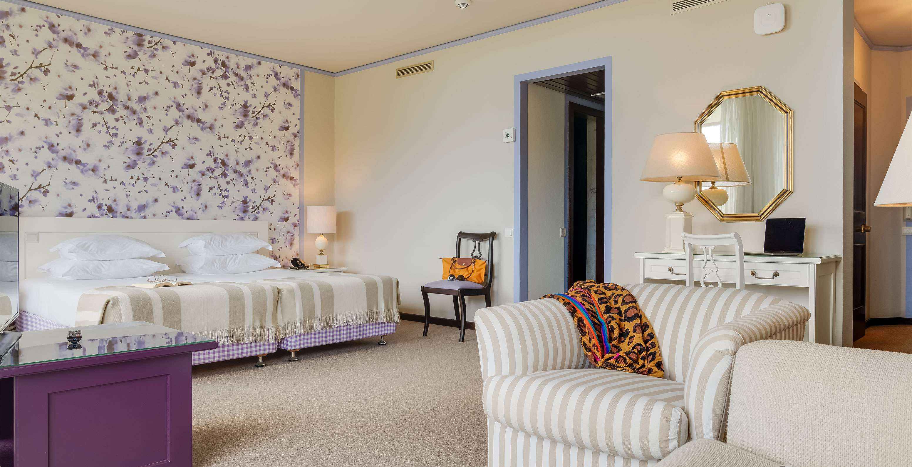 In the Junior Garden View Suite at Pestana Bahia Praia, beds are next to the balcony, with views of gardens and sea