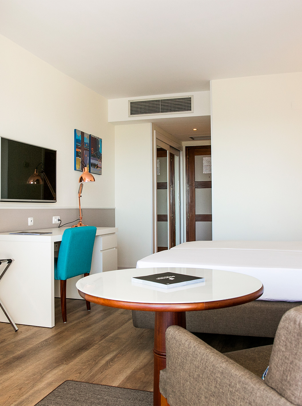 The Deluxe Sea View room at Pestana Cascais has two single beds, a TV, a desk, and a kitchenette