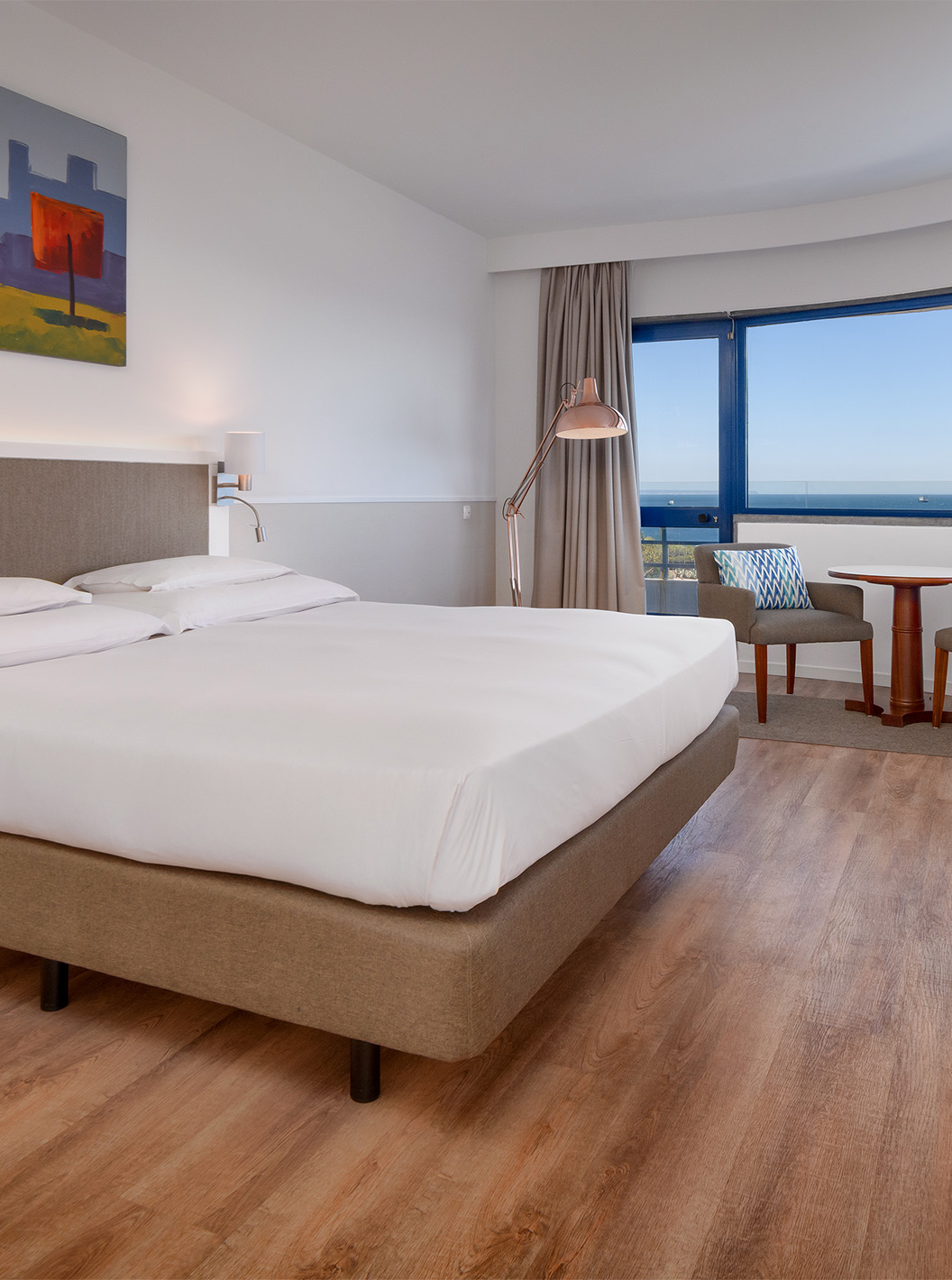 The Deluxe Sea View Suite at Pestana Cascais has a double bed, a TV, and a painted picture on the wall