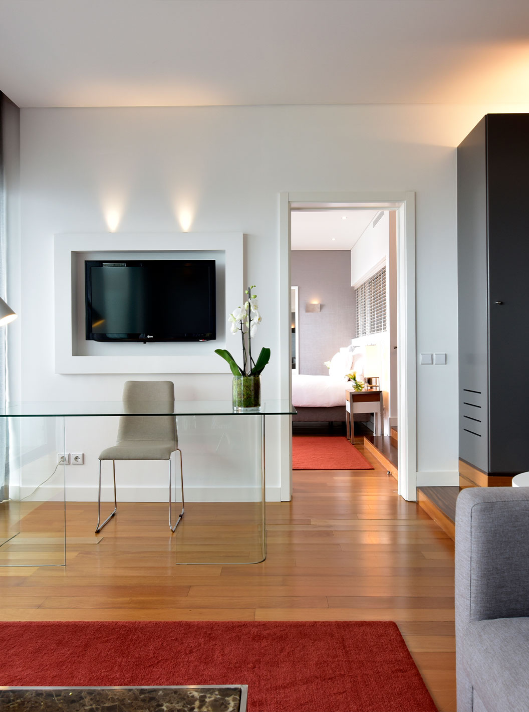 The Suite at Pestana Cidadela Cascais has a living room with a gray sofa, TV, desk, and table