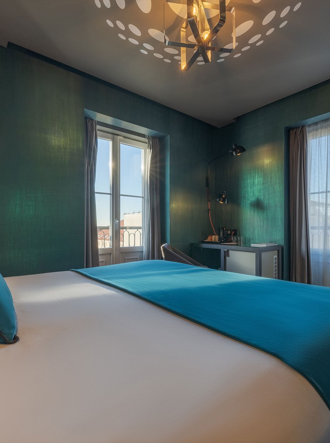 The CR7 Superior Corner Room at Pestana CR7 Lisboa features a bed and two windows overlooking Lisbon's Historic Center