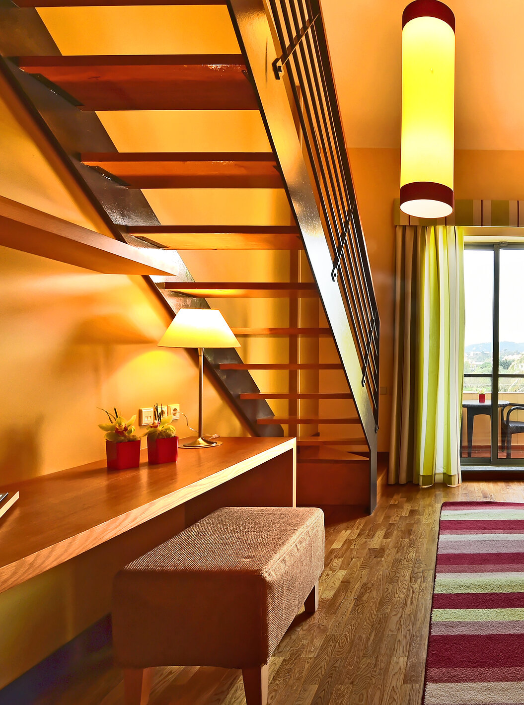 The Family Mezzanine Suite of Pestana Sintra Golf has a room with a large sofa, mirror, and a window with balcony access
