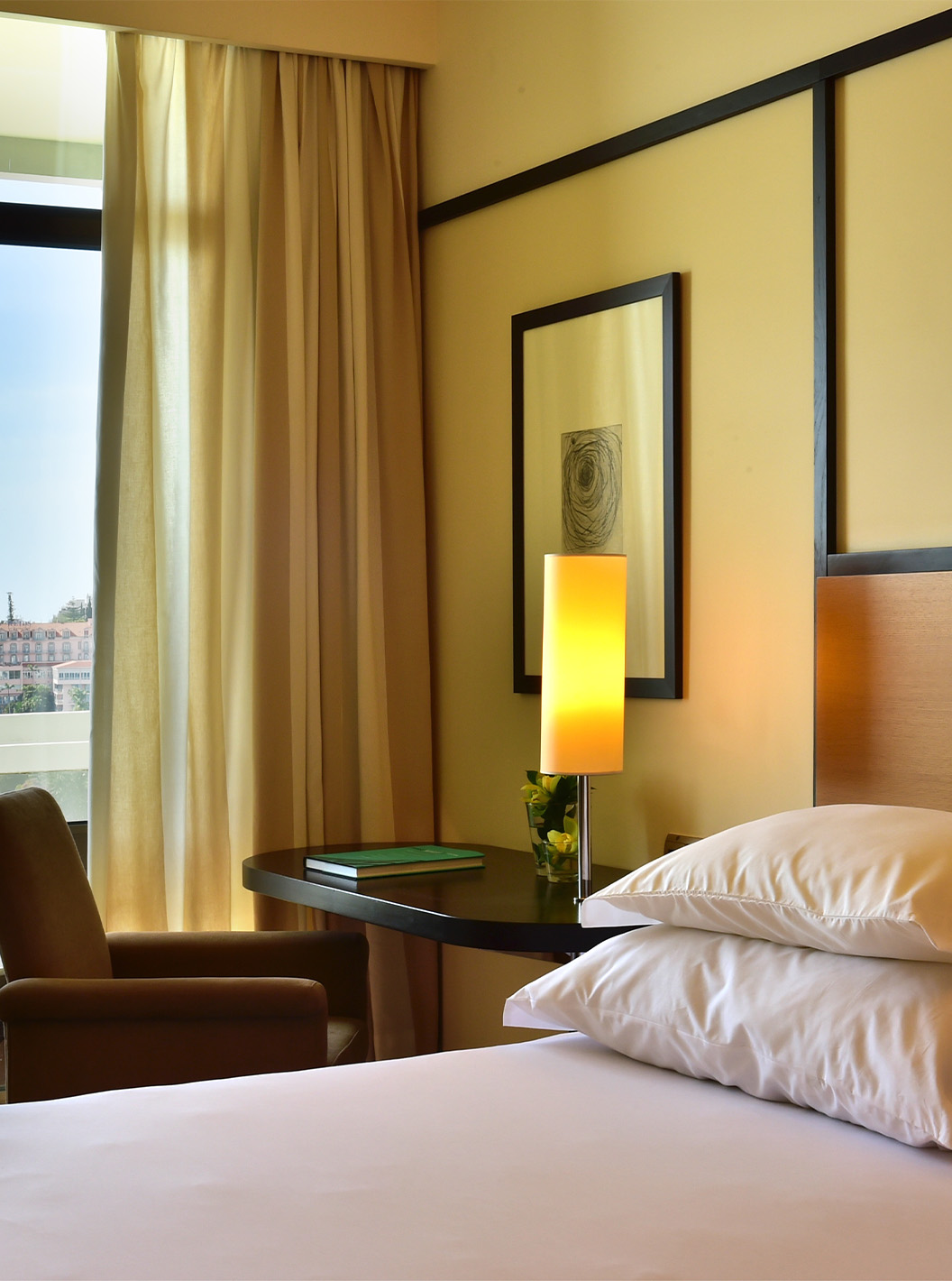 The Sea View Suite at Pestana Casino Park has a double bed, a desk with a lamp, and a balcony
