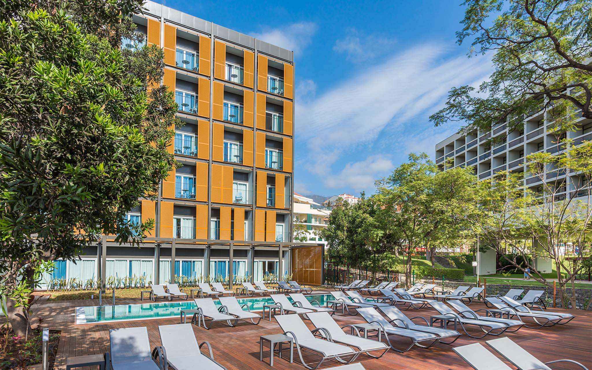 Exterior view of Pestana Casino Studios, with apartments in the city center, featuring a pool and an orange building