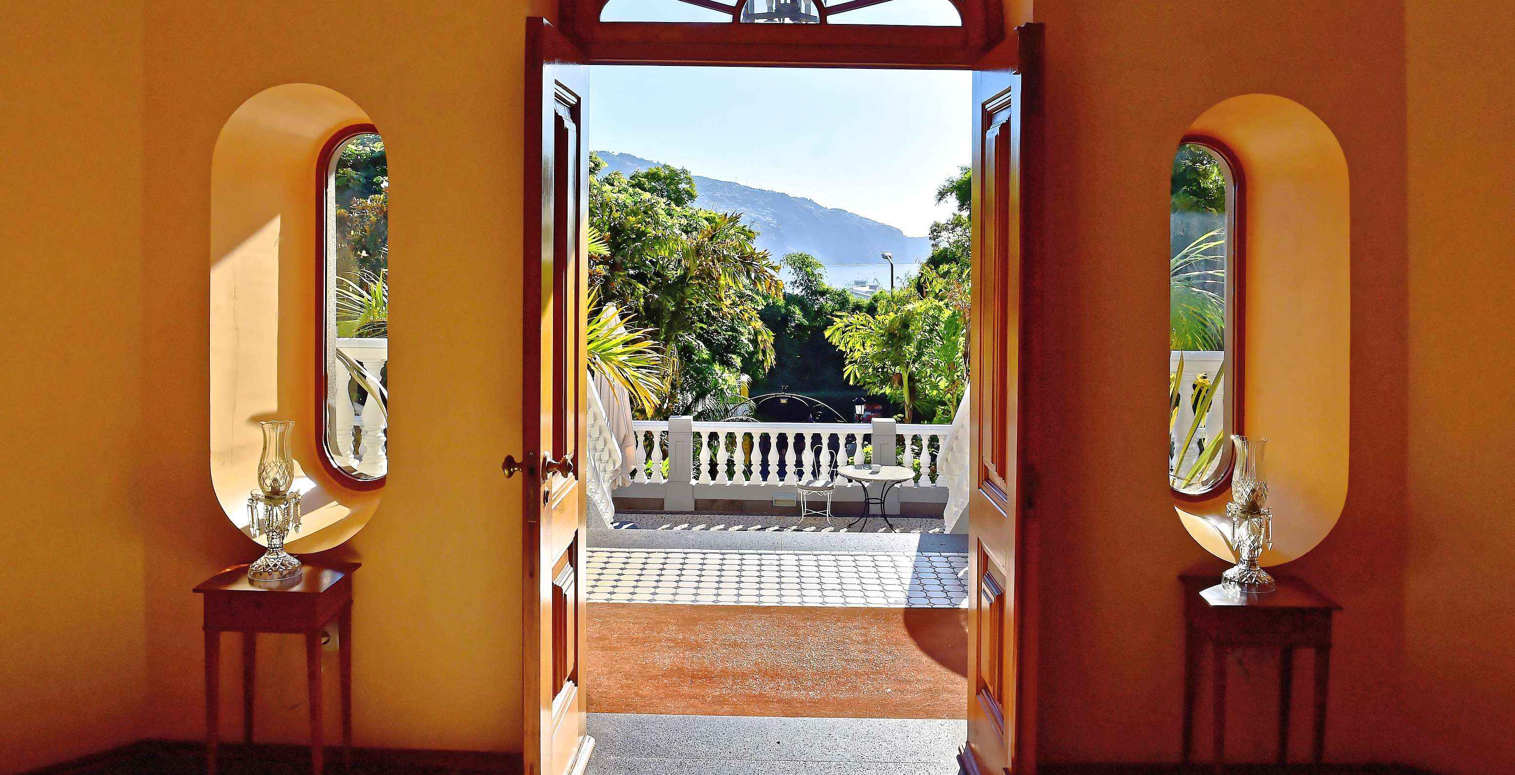 View from the balcony of Quinta Miramar, a hotel in Madeira near the beach, with pool surrounded by nature