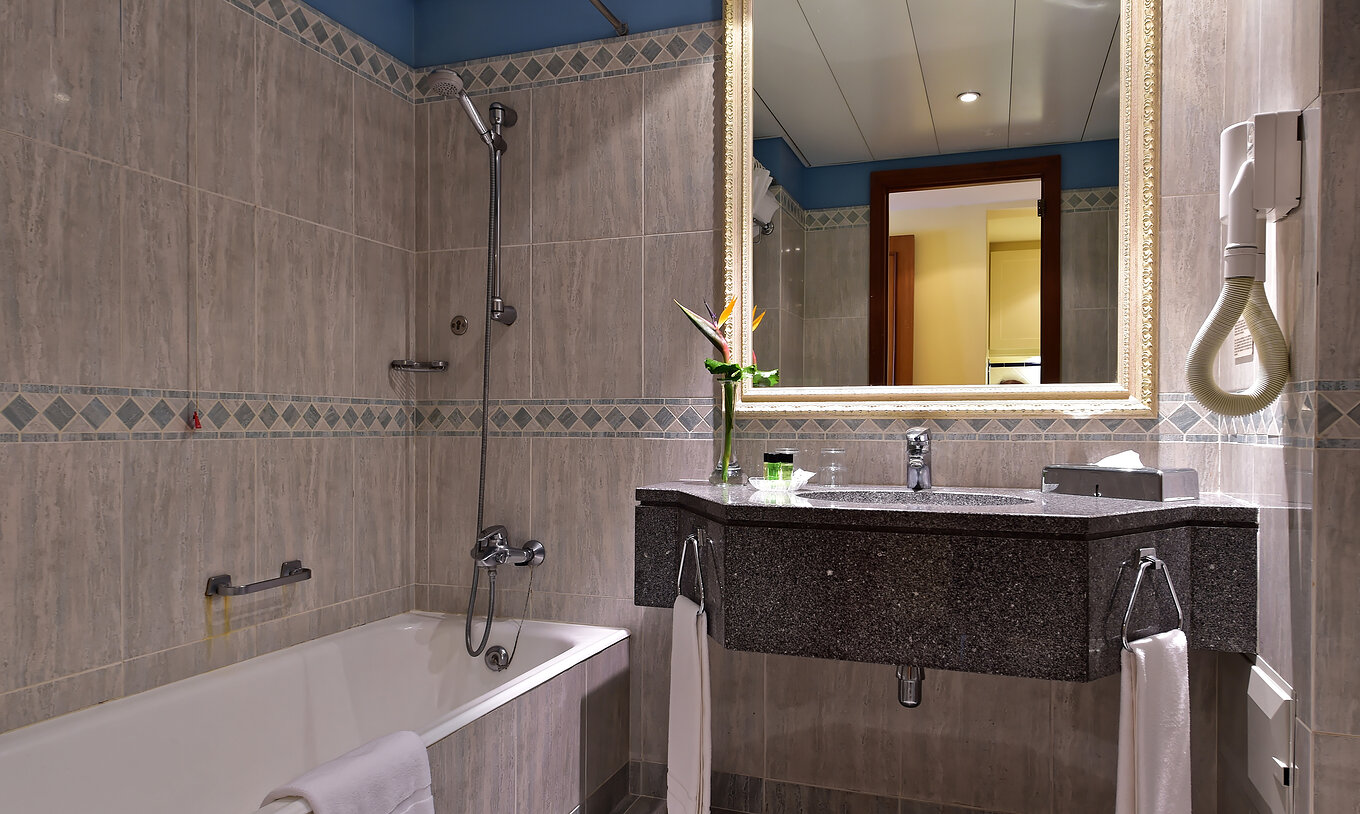 The Superior Room at Pestana Miramar has a bathroom with gray tiles, bathtub and a dark sink