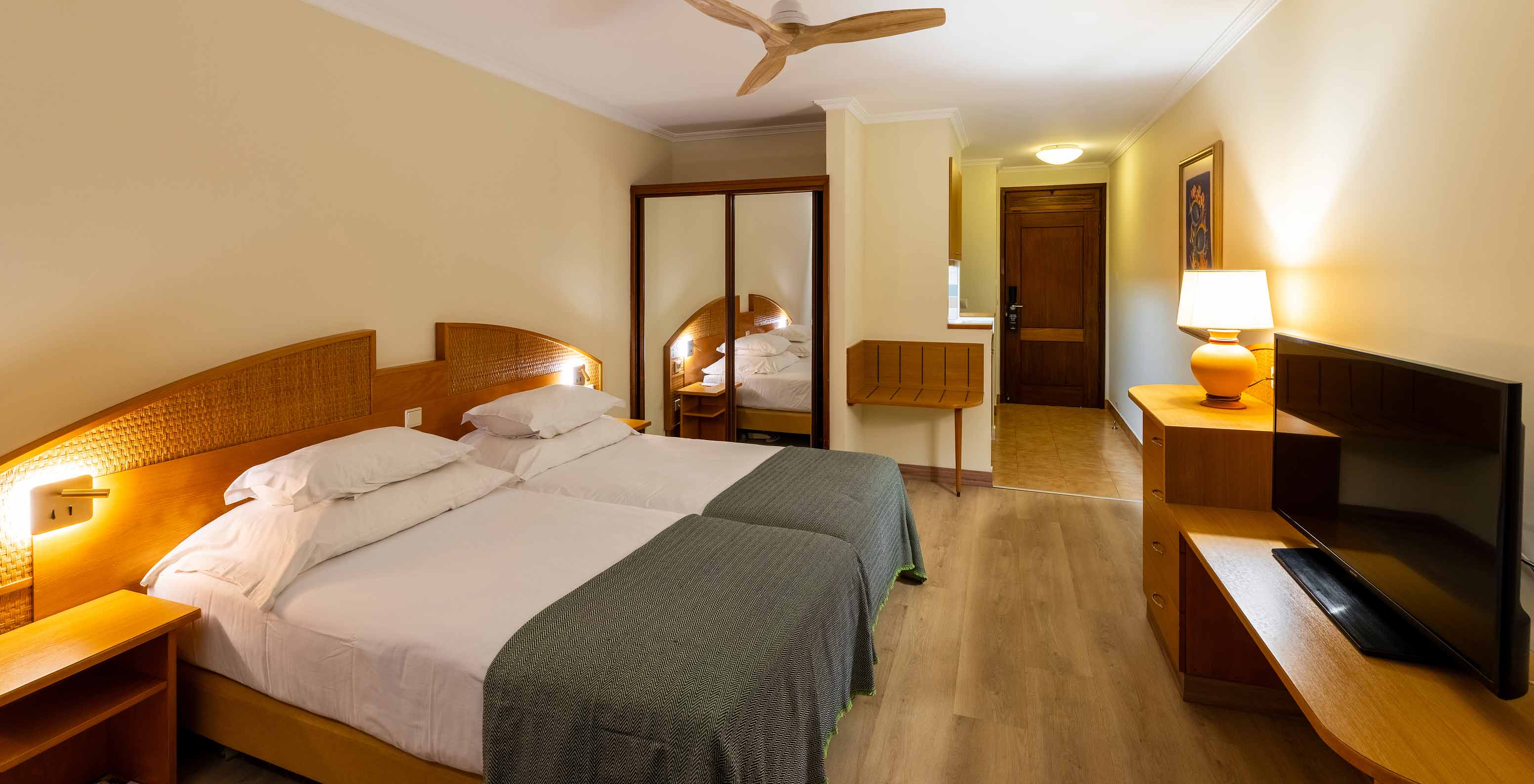 The Pestana Ocean Bay All Inclusive Superior Sea View has a double bed, a TV cabinet, a luggage rack, and a mirror