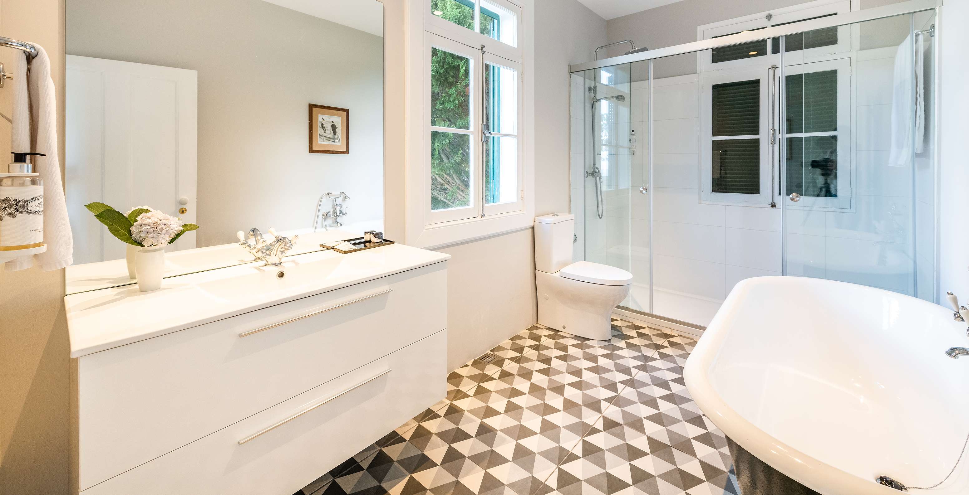 The Full Manor House of Pestana Quinta do Arco has a bathroom with bathtub and shower, sink with large mirror, and window