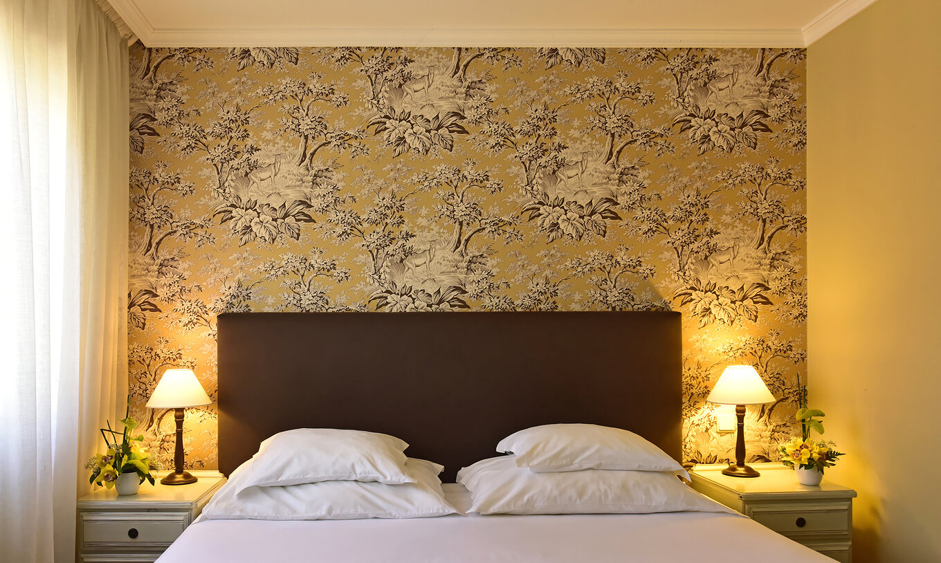 The Suite with Jacuzzi at Pestana Village has a double bed with headboard and brown bedspread, and wallpaper