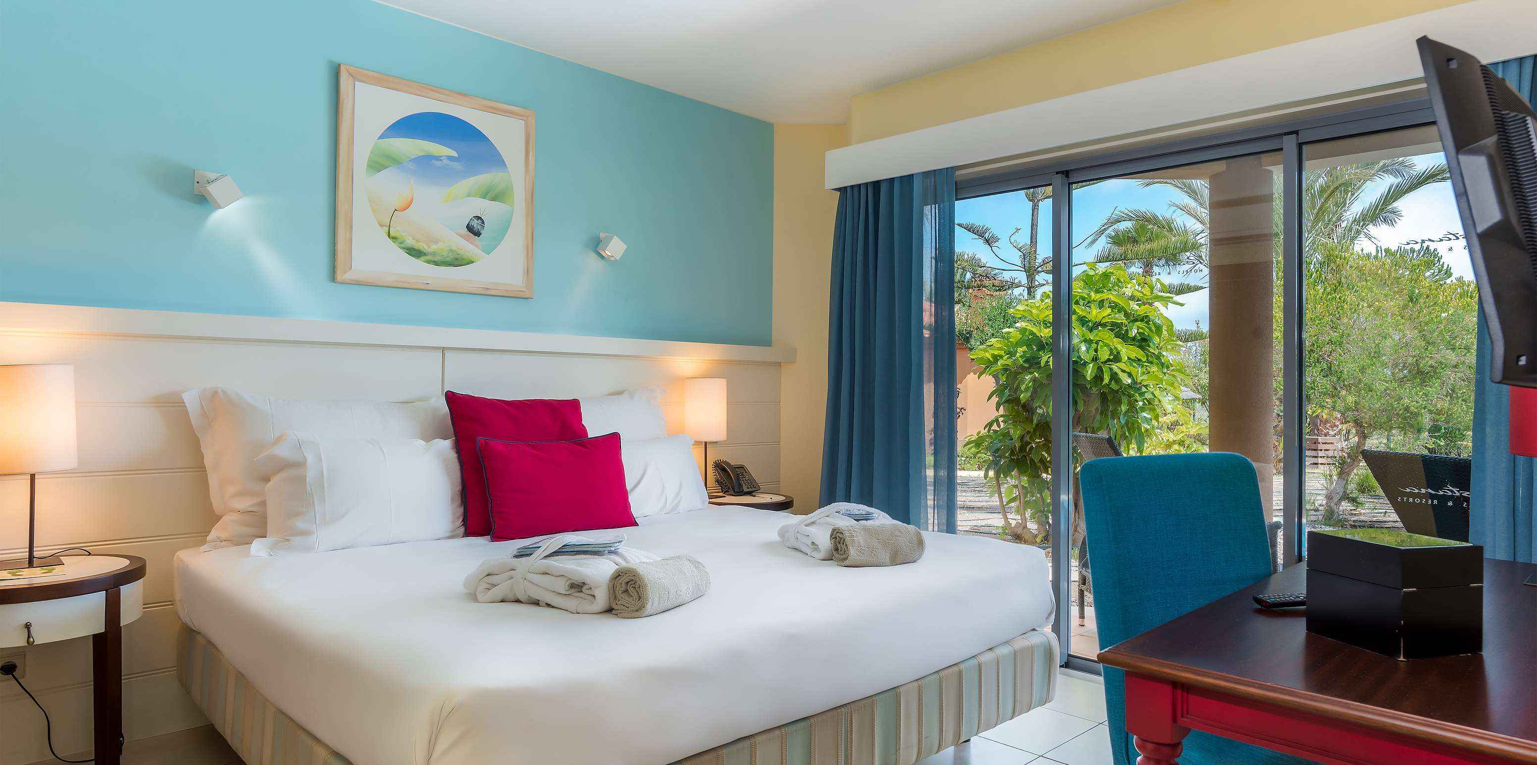 The Pool Villa of Pestana Porto Santo All Inclusive has a blue-toned bedroom with a double bed and a large window