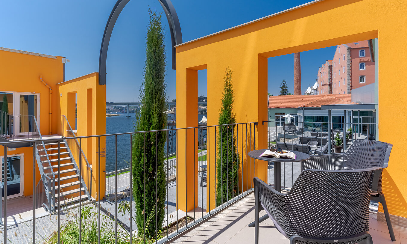 The River View room at Pestana Douro Riverside features a balcony with a table and chairs, overlooking the Douro River