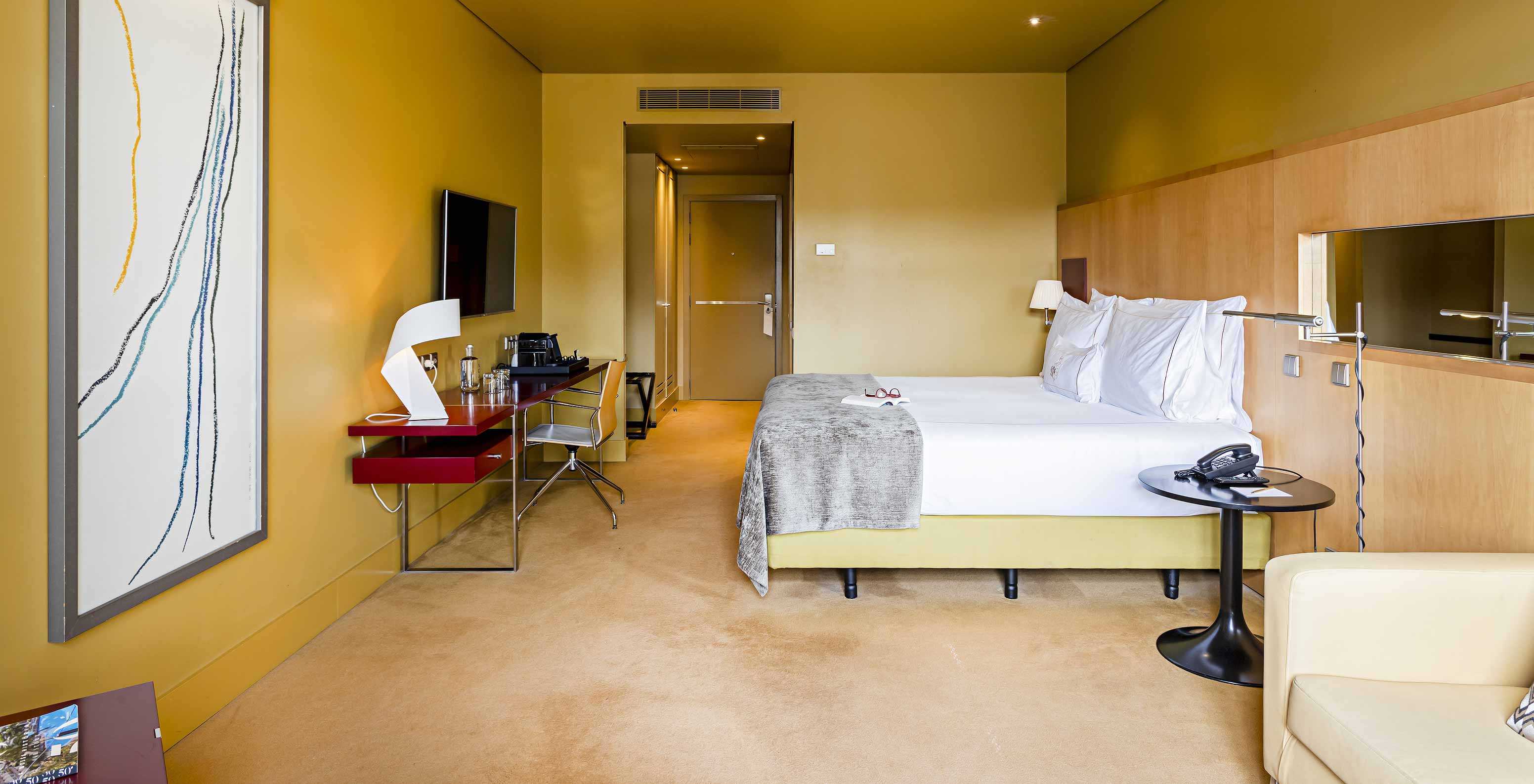 Pestana Palácio do Freixo’s Superior room has a double bed with grey cover and a desk