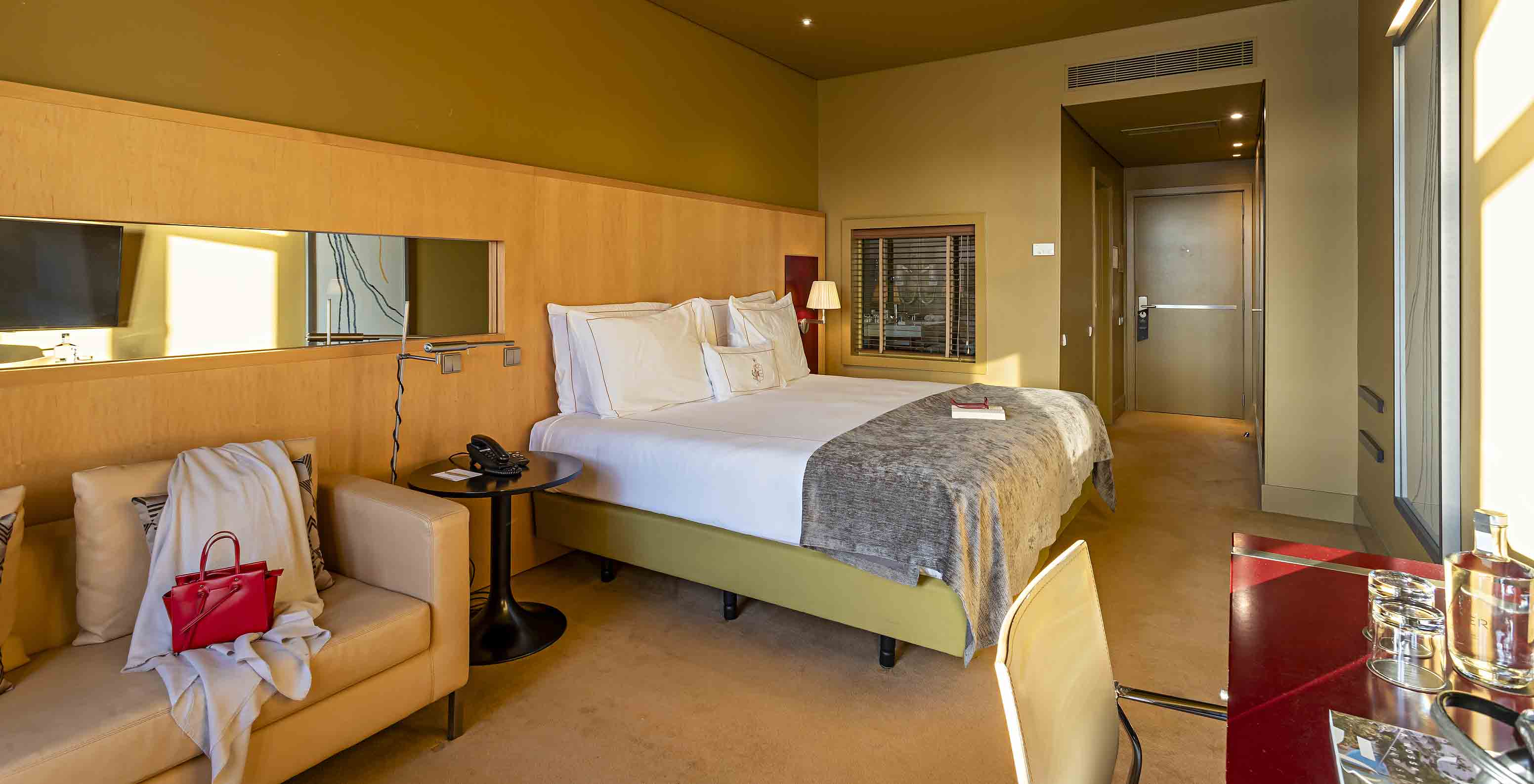 The Executive Superior has a double bed, a sofa, and a red desk