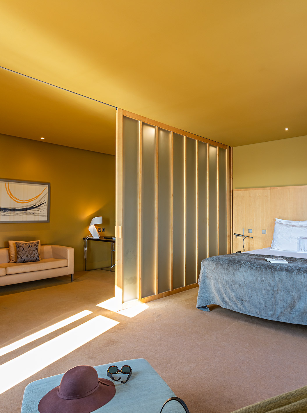 The Standard Suite has a large double bed with a grey blanket and a sofa