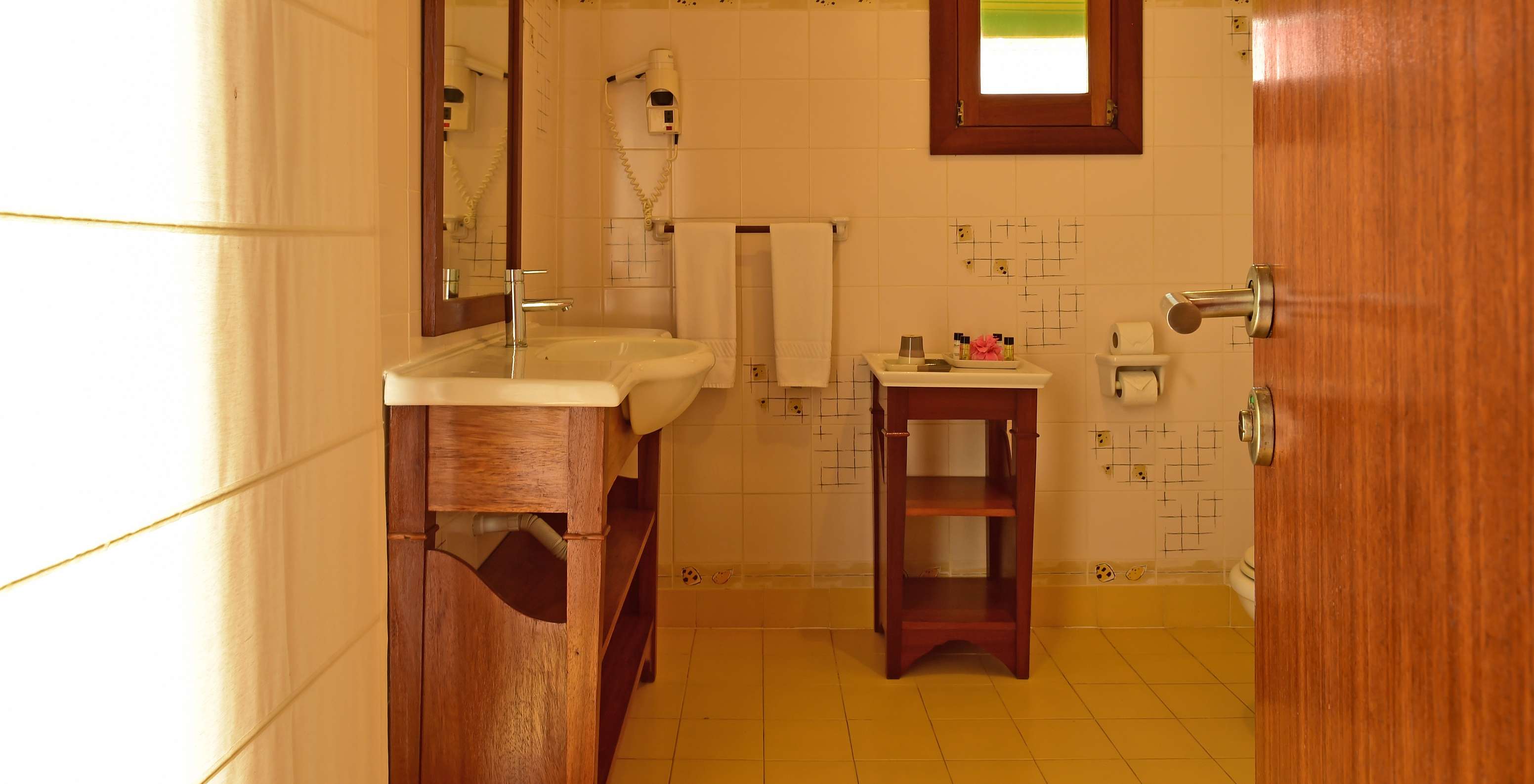 The Superior Double at Pestana Equador Ilheu das Rolas has a bathroom with a sink, mirror, hairdryer, and window