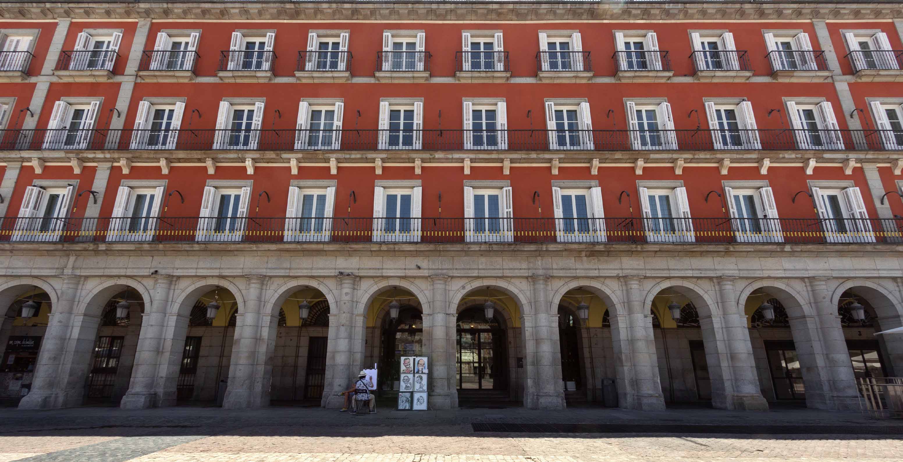 Facade of Pestana Collection Plaza Mayor building, painted in red tones with multiple windows during the day